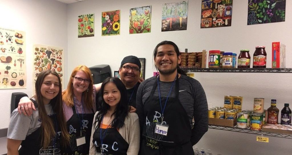 Four students and a professor standing in front of Aztec Resources food bank