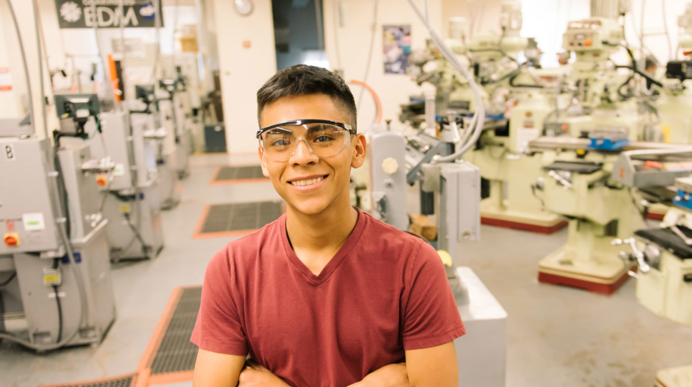 Student with safety goggles stands in a shop class