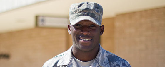 A member of the United States Army in camouflage, smiling for a photo.